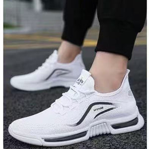 White sneakers with black accents being worn and tied by a person.