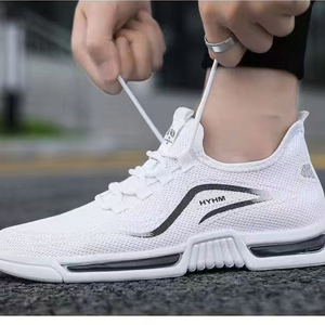 White sneakers with black accents being worn and tied by a person.