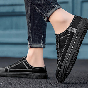 Black sneakers worn with rolled-up jeans on a blurred background
