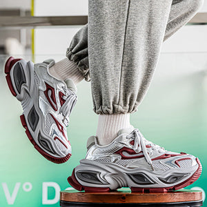 A person wearing chunky white, gray, and red athletic sneakers with white socks, shown from the knees down while sitting on a stool. The background is a soft green gradient with text overlays.