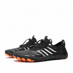 Black water shoes with orange soles on a sandy beach