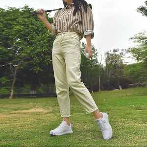 Person playing golf on a grassy course with trees in the background