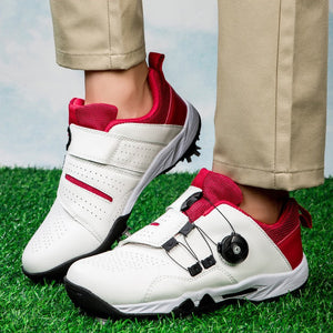 White and red casual golf shoes with a dial closure system, shown on a model wearing khaki pants standing on artificial grass.