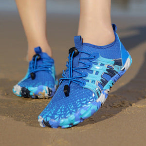 A pair of bright blue athletic water shoes with a black and light blue abstract pattern, shown on a model's feet on a sandy beach. The image is a split-screen view showing different angles of the shoes being worn, with a gray border and text at the bottom.
