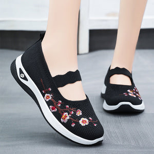 Black shoes with floral embroidery on a gray floor