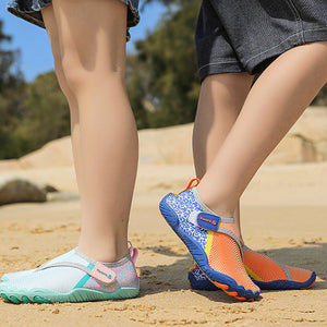 A person outdoors on sandy ground wearing two pairs of water shoes: one light aqua and white with pink accents, and one blue and orange with purple details. The photo is cropped from the waist down, with denim shorts and dark shorts visible, and a blue border with the text 'COOL SUMMER'.