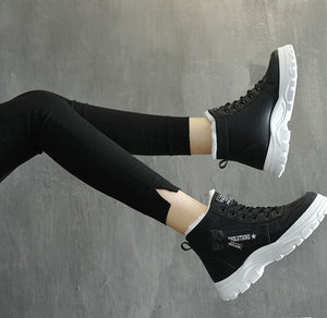 Black high-top platform sneakers with chunky white soles, shown on a model wearing black leggings against a gray concrete-textured background.
