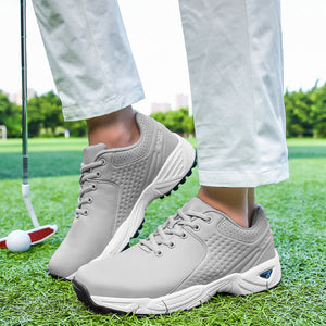 A person wearing light gray golf shoes on a green golf course, with white pants visible from the knees down and a golf club in the background.