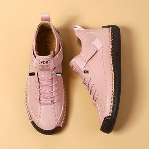 Pair of pink sneakers with black soles on a beige background