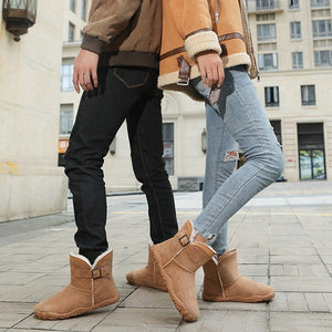 A couple wearing tan shearling-lined ankle boots and brown jackets walking outdoors on a city sidewalk, with text at the top reading 'Outdoor travel couple style' and 'Warmth meets velvet in the winter'.