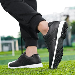 A person wearing black low-top sneakers with white soles, standing on green grass outdoors. The photo is cropped to the lower legs and feet, with a black banner at the top containing promotional text and a black banner at the bottom with 'Sellingpointdisplay'.