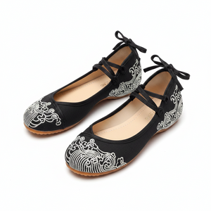 A pair of black flat shoes with traditional Chinese wave embroidery in white and black, featuring lace-up straps and bow details on the back, shown on a white background.