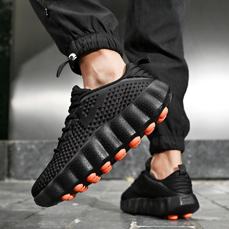 Black casual shoes with orange accents worn by a person in black pants.