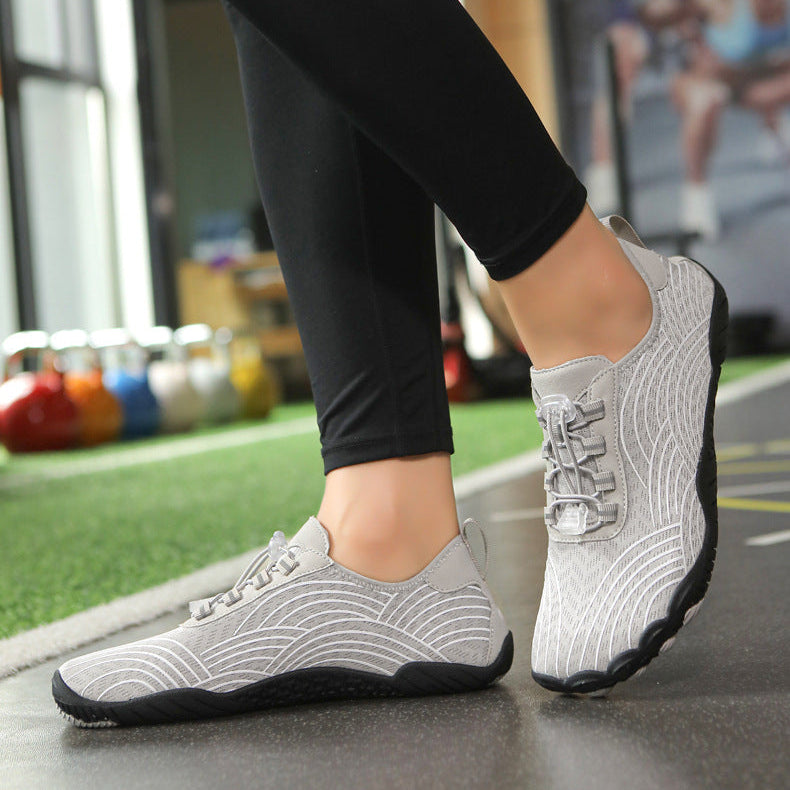 A pair of light gray knit athletic sneakers shown on a model in a gym setting, with the model wearing black leggings in the top view and black and blue leggings in the bottom view.