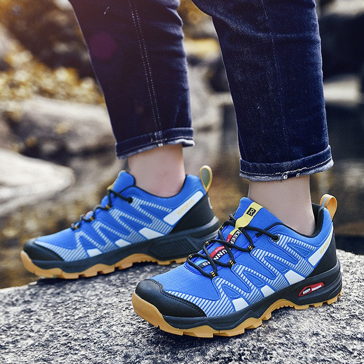 A person wearing blue and black hiking shoes with tan soles, standing on a rocky outdoor surface. The image includes promotional text at the top describing comfort and style.