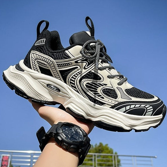 Black and white sneaker held in a hand with a clear blue sky background