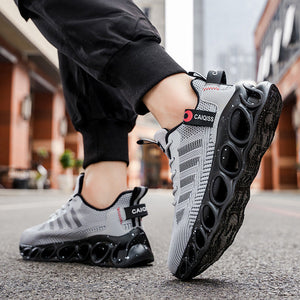 A person wearing black jogger pants and gray and black athletic sneakers with a unique circular sole, standing on an urban street. The text 'RESTORING ANCIENT WAYS' is displayed at the top of the image.