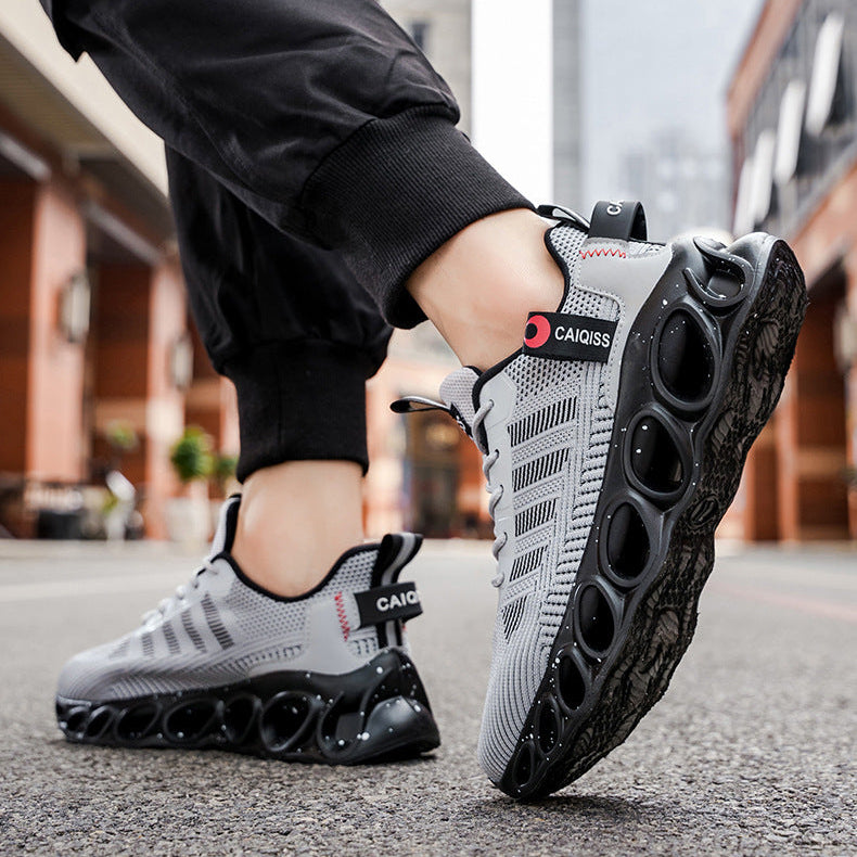 A person wearing black jogger pants and gray and black athletic sneakers with a unique circular sole, standing on an urban street. The text 'RESTORING ANCIENT WAYS' is displayed at the top of the image.