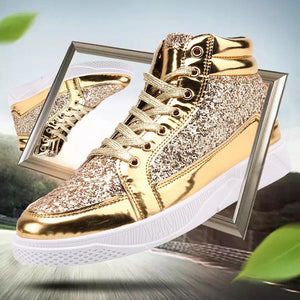 A pair of high-top sneakers with metallic gold and glittery silver panels, white laces, and white soles, shown with a tilted mirror reflection effect and promotional text on a blurred outdoor background.