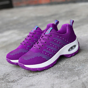 Purple running shoes with white soles on a concrete surface