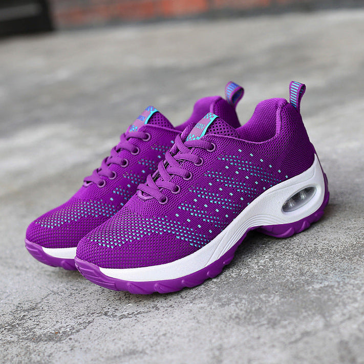 Purple running shoes with white soles on a concrete surface