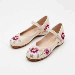 A pair of women's flat shoes in a warm cream color, decorated with pink and gold floral embroidery on the toes and sides, featuring a strap across the instep.