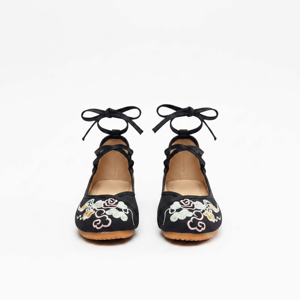 A pair of black flat shoes with lace-up ankle straps and embroidered floral details on the toe, shown from the back against a plain white background.