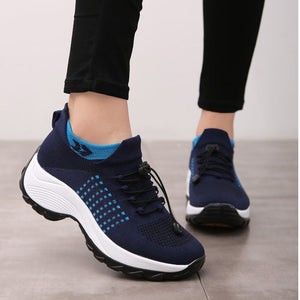 Navy blue athletic shoes with white soles worn indoors on a light gray floor.