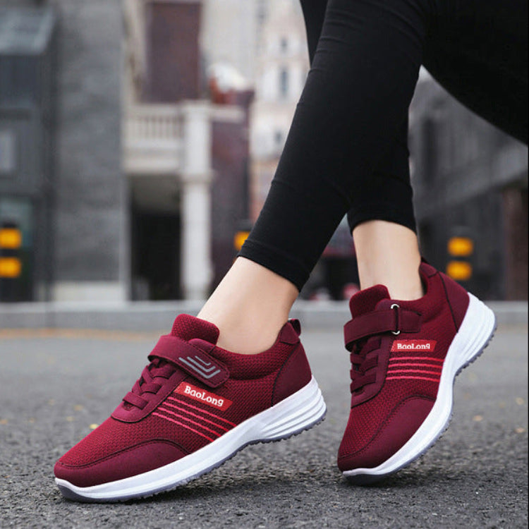 A pair of women's low-top athletic sneakers in burgundy red and white, featuring hook-and-loop strap closures and a visible 'SooLong' brand logo. The top half shows the shoes being worn by a person in an outdoor urban setting, while the bottom half shows a clean close-up of the shoes on a paved surface.