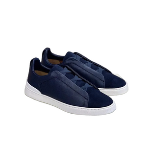 Navy slip-on sneakers on a light green box with a neutral background