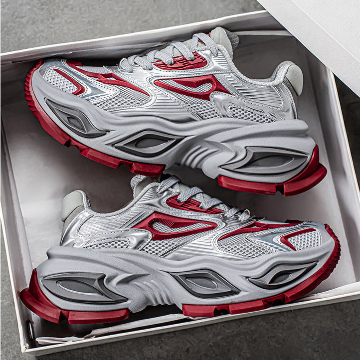 A pair of chunky platform sneakers in white, gray, and red, displayed inside an open white shoebox on a gray surface.