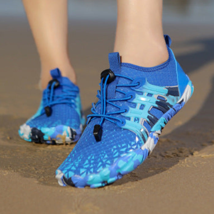 A pair of bright blue athletic water shoes with a black and light blue abstract pattern, shown on a model's feet on a sandy beach. The image is a split-screen view showing different angles of the shoes being worn, with a gray border and text at the bottom.