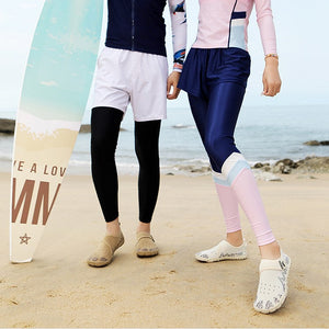 A man and a woman standing on a sandy beach wearing matching long-sleeve athletic rash guards and swim trunks, with a surfboard beside the man. Text at the top reads 'Stroll - "airy feel"' and 'Effortlessly ride the waves and unwind freely.