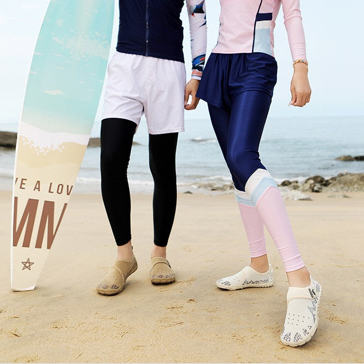 A man and a woman standing on a sandy beach wearing matching long-sleeve athletic rash guards and swim trunks, with a surfboard beside the man. Text at the top reads 'Stroll - "airy feel"' and 'Effortlessly ride the waves and unwind freely.