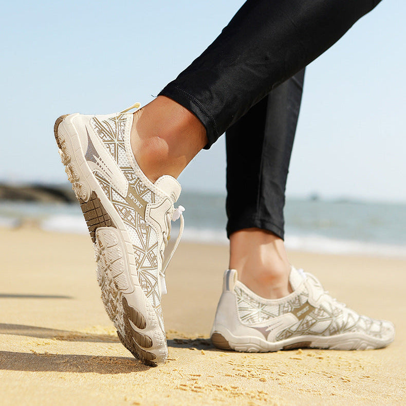 Person wearing white sneakers with patterned design on a beach