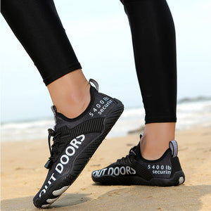 Black sneakers with 'Outdoors' branding on a beach