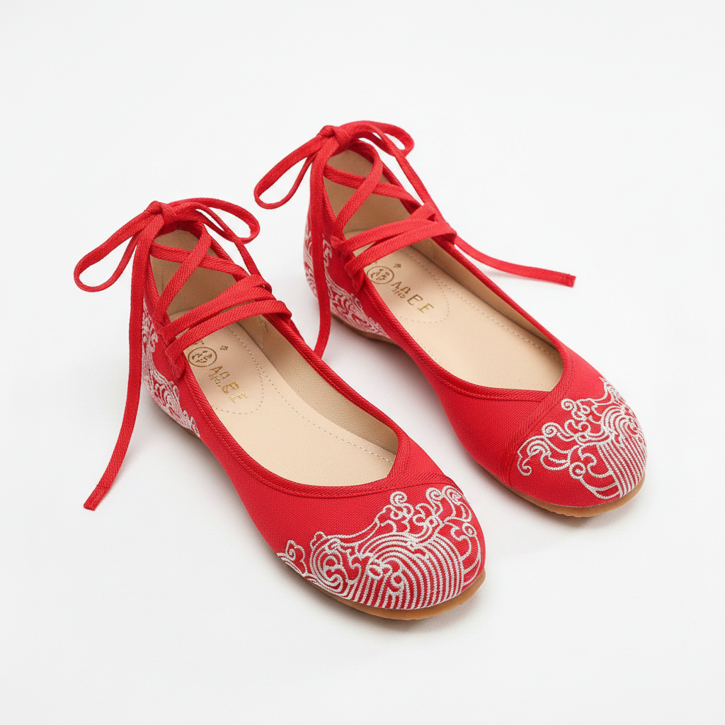 A pair of red flat shoes with white wave embroidery on the toe and side, featuring lace-up front straps and a low heel, photographed on a clean white background.