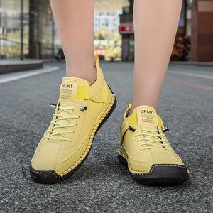 Yellow sneakers worn by a person on a city street.