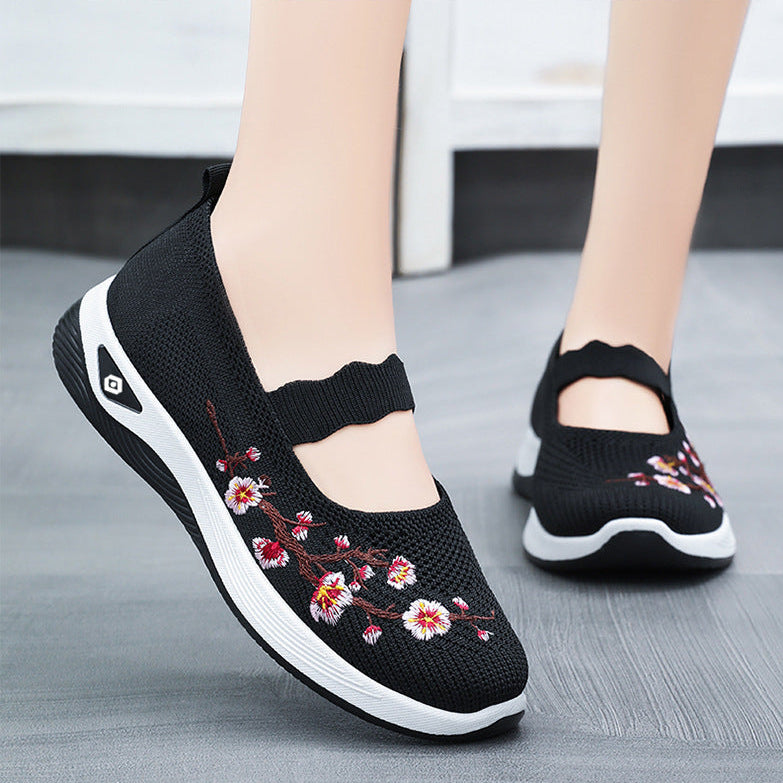 Black shoes with floral embroidery on a gray floor