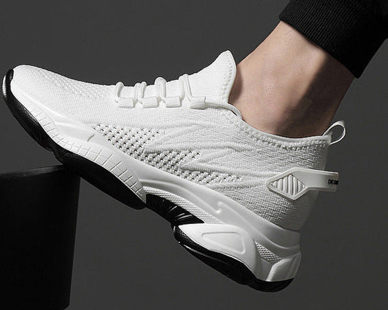 A white athletic sneaker with black sole details, shown being worn on a person's foot against a dark gray background.