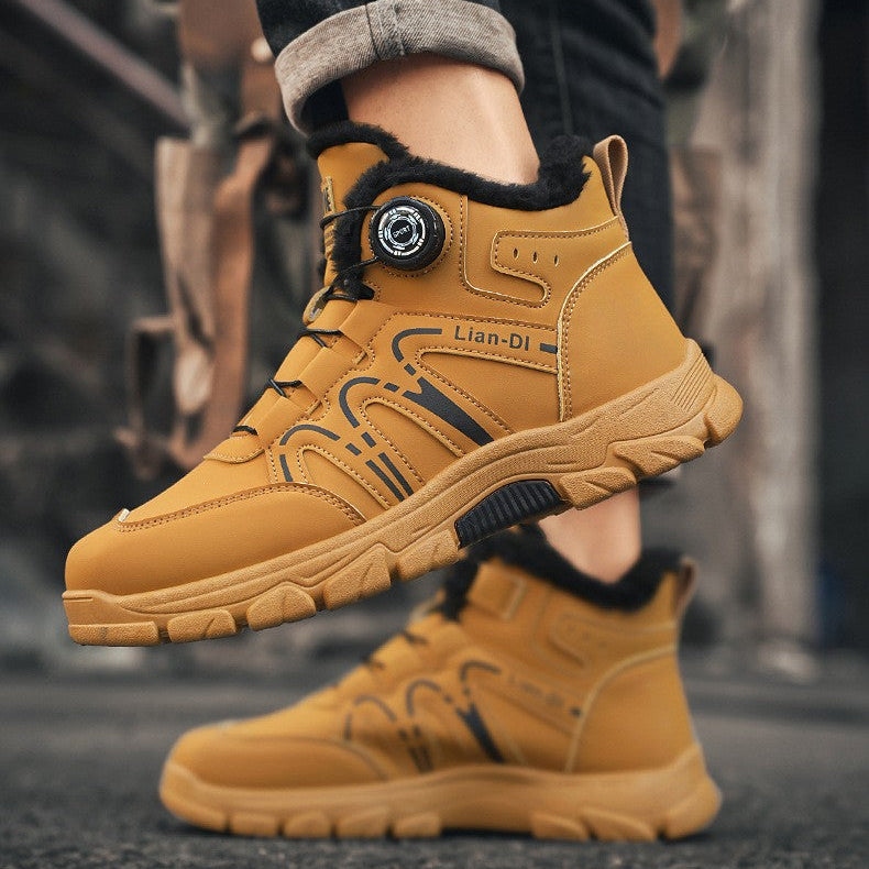 A person wearing tan mid-calf winter boots with black trim and dark cuffed jeans, shown against an urban street background. The boots have a circular dial closure and thick lug soles.