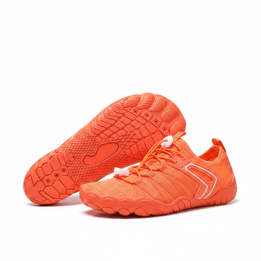 A pair of bright orange mesh athletic water shoes with white laces and white trim, displayed on a light wooden surface with a blue gradient background and a wire stand.