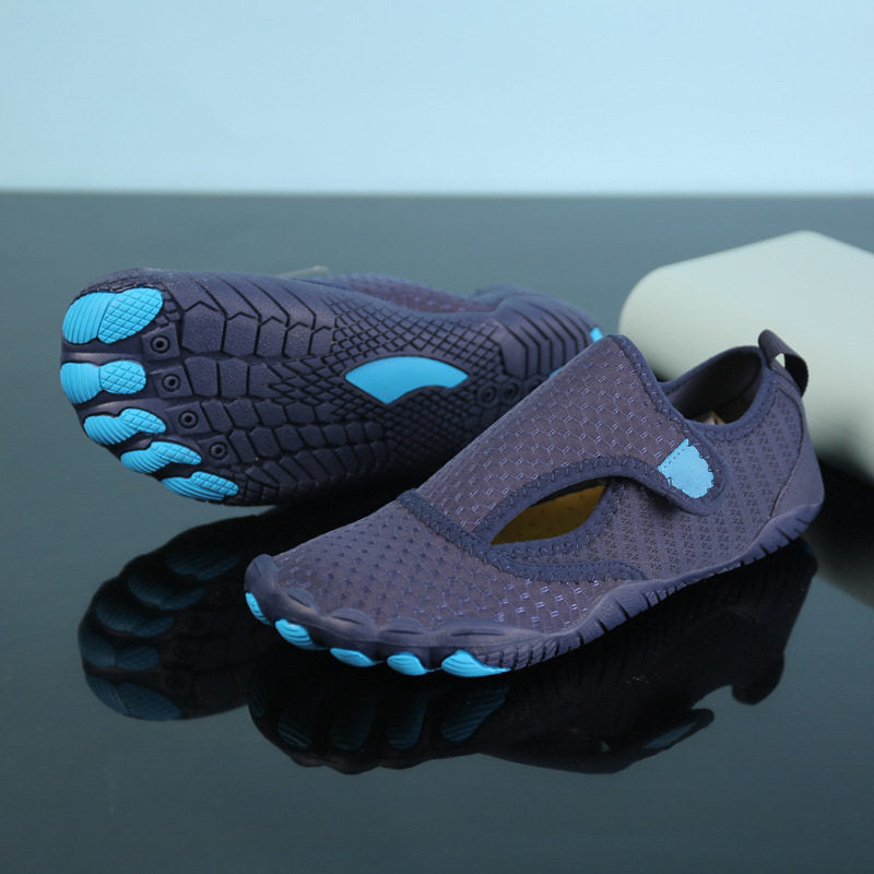 A pair of dark purple water shoes with bright blue accents on the sole and footbeds, displayed on a reflective black surface.