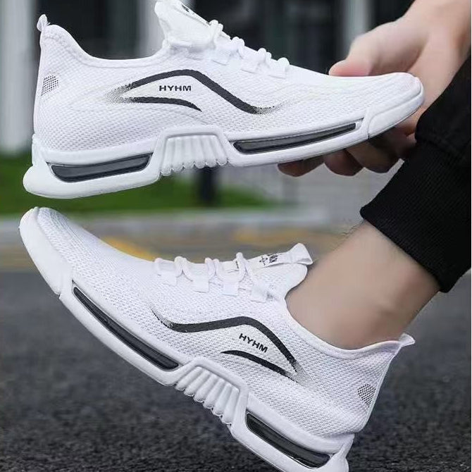 White athletic sneakers with black accents, shown being worn and held by a person outdoors on a paved surface.