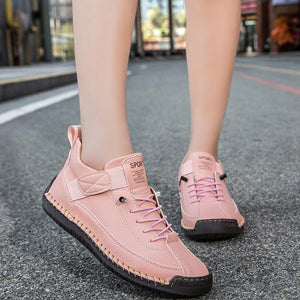 Pink sneakers worn by a person on a city street.