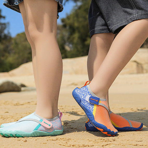 A person outdoors on sandy ground wearing two pairs of water shoes: one light aqua and white with pink accents, and one blue and orange with purple details. The photo is cropped from the waist down, with denim shorts and dark shorts visible, and a blue border with the text 'COOL SUMMER'.