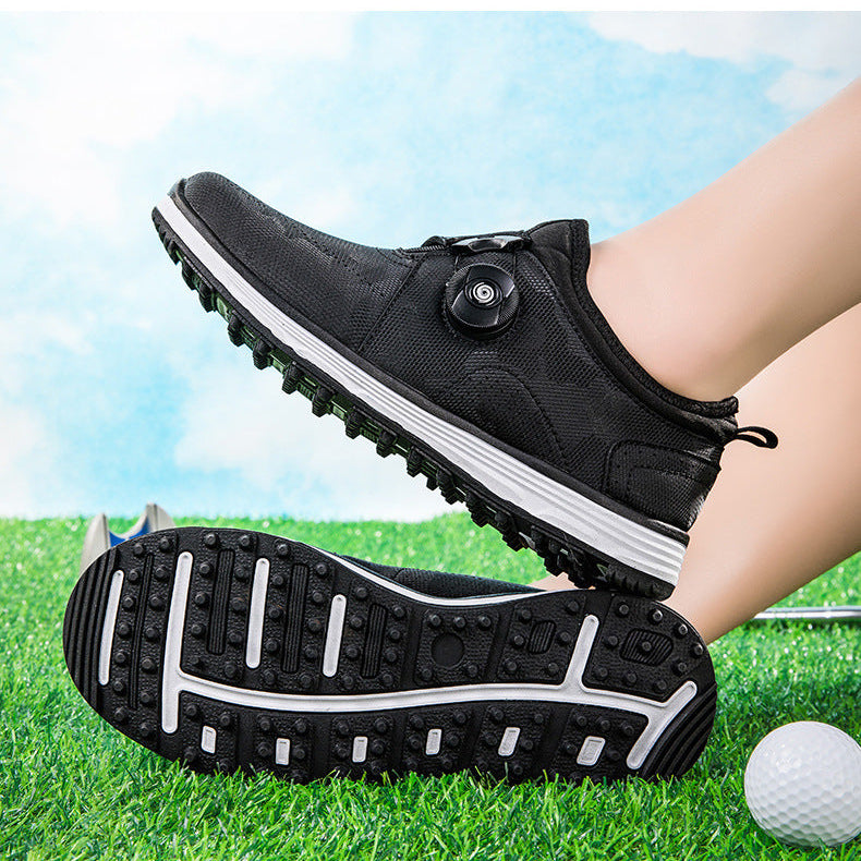 Black low-top golf shoes with a dial closure and white midsoles, shown on a person's foot and sole against a grassy golf course background with a golf ball.
