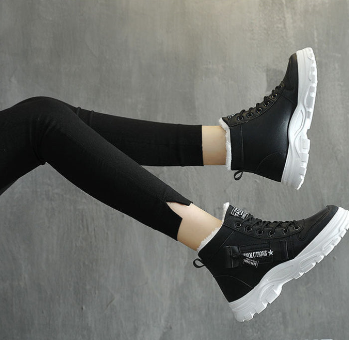 Black high-top platform sneakers with chunky white soles, shown on a model wearing black leggings against a gray concrete-textured background.