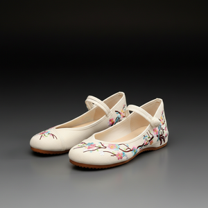 A pair of cream-colored Chinese-style ballet flats with floral embroidery on the toes, displayed on a dark gray gradient background.
