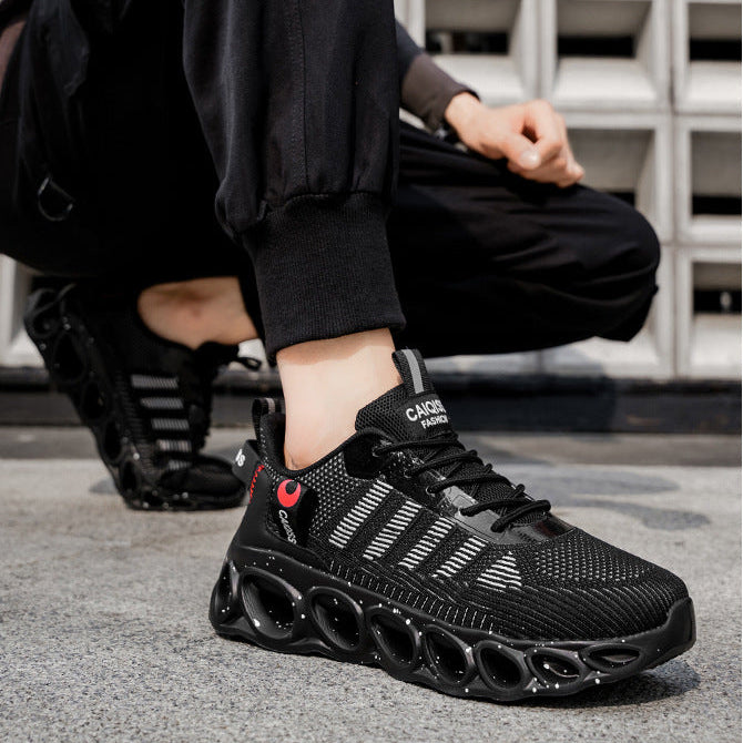 A person wearing black athletic sneakers with textured knit uppers and chunky black soles, crouching outdoors on a gray pavement in front of a white block wall. The image includes the text 'SPORTS SHOES fashion sport' at the top.